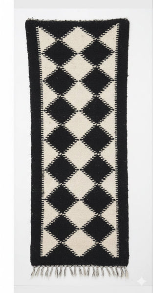 Black and white diamond patterned rug on a white background