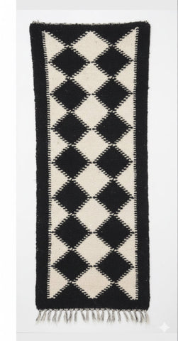 Black and white diamond patterned rug on a white background